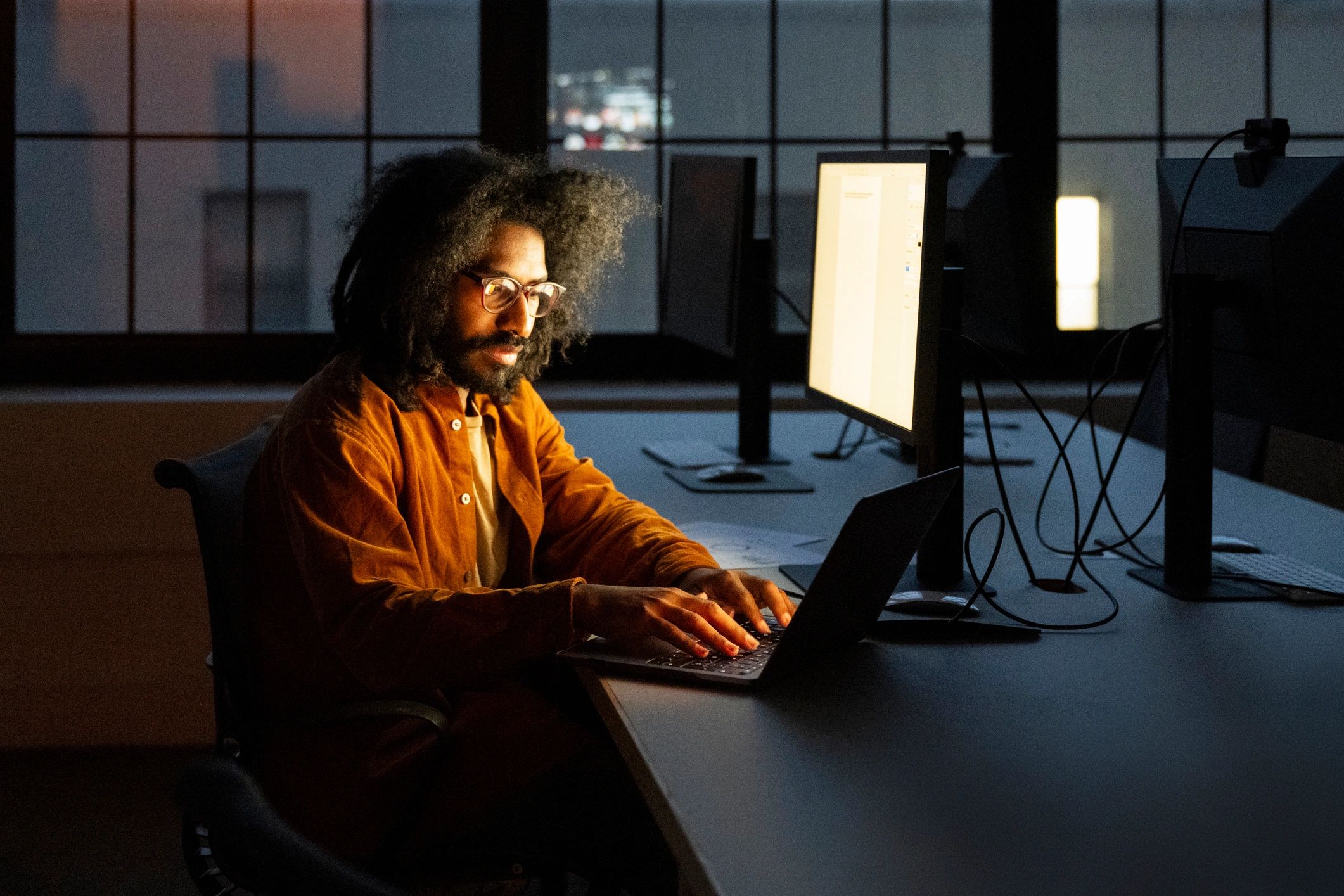 Security professional working on a laptop in a dark office